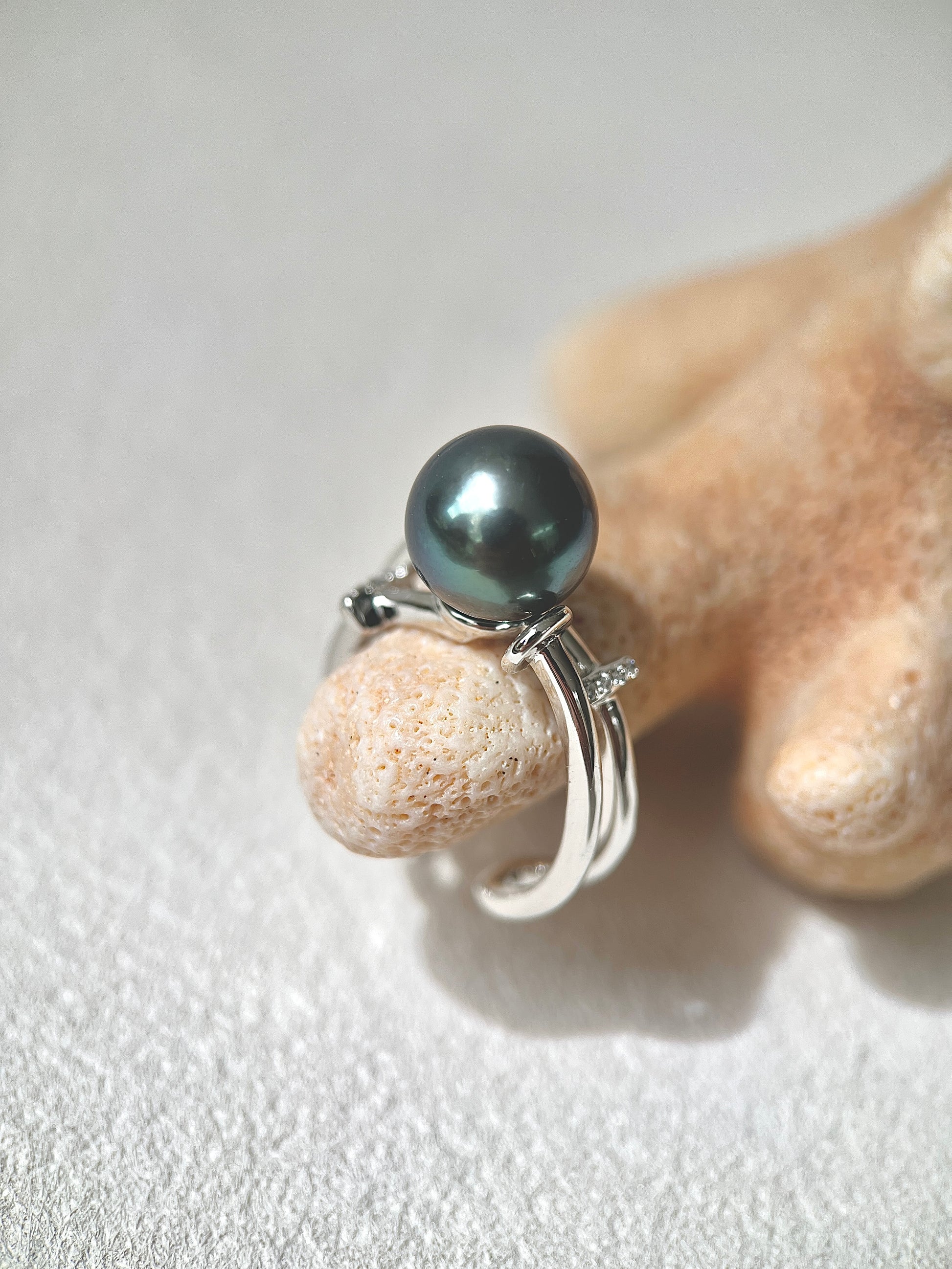 Silver ring with a large black Tahitian pearl on a textured surface