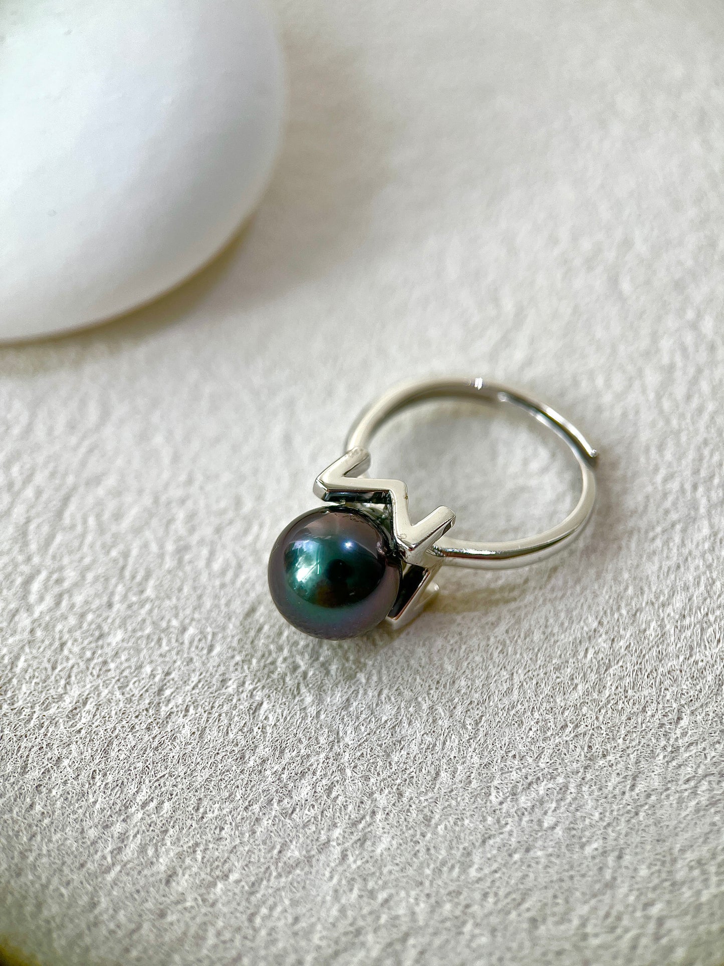 Silver ring with a black pearl on a light gray background