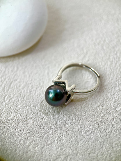 Silver ring with a black pearl on a light gray background