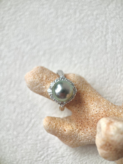Silver ring with a large pearl on a textured beige surface