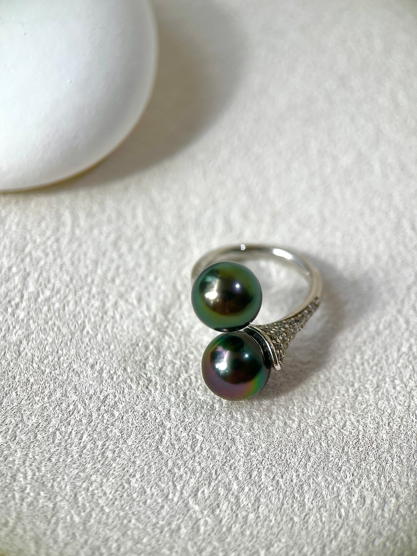 Silver ring with black pearls on a light gray surface