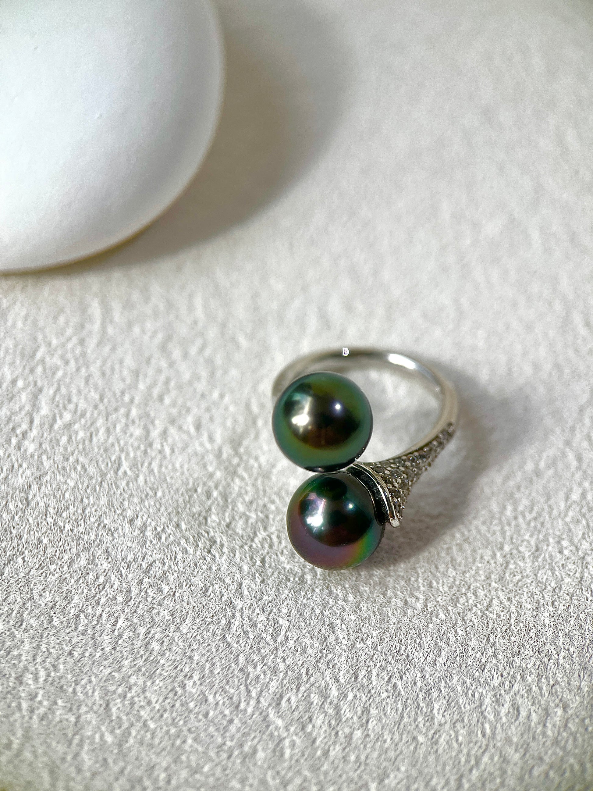 Silver ring with black pearls on a light gray surface