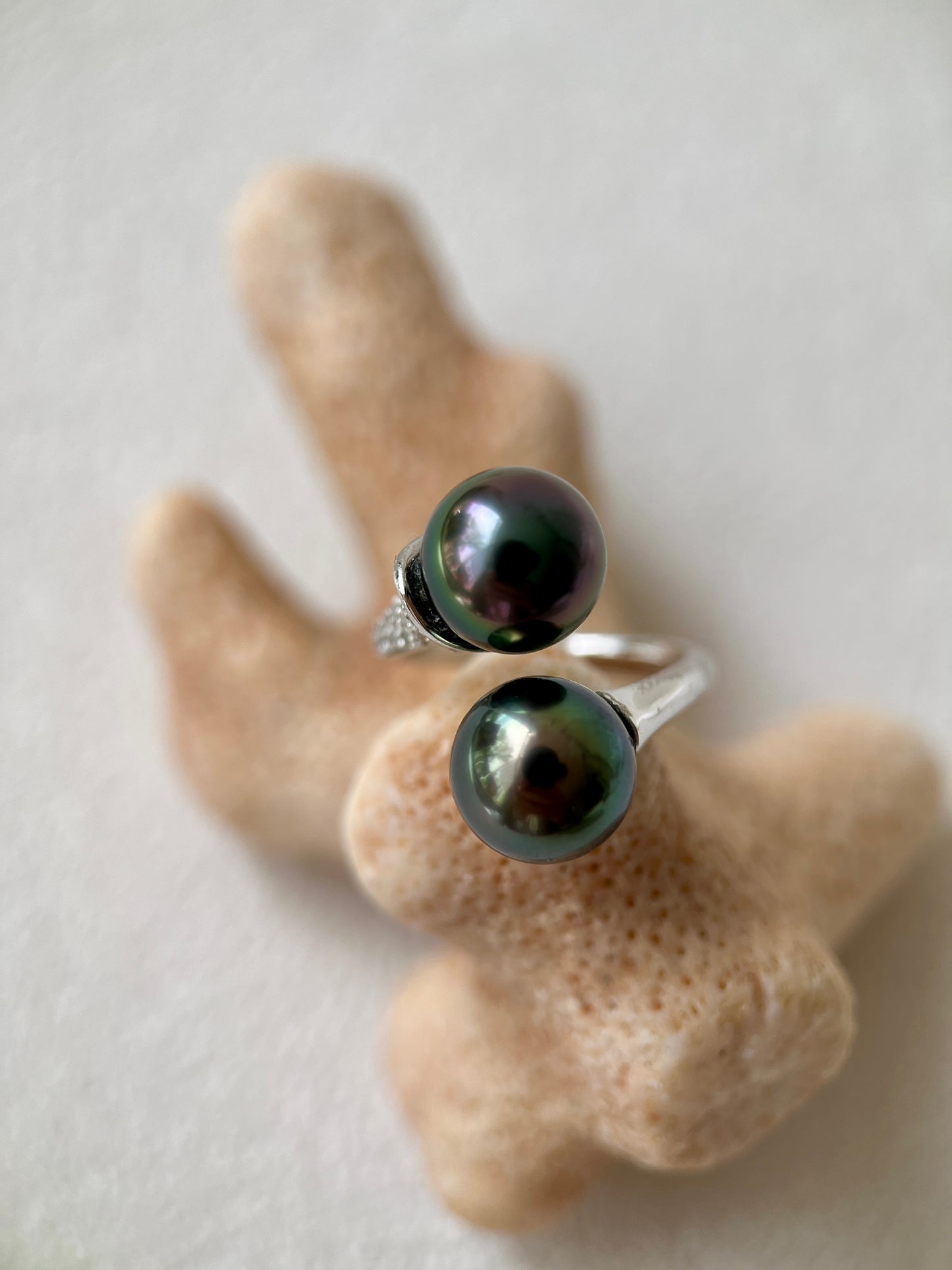 Two black pearl rings on a beige coral-like surface