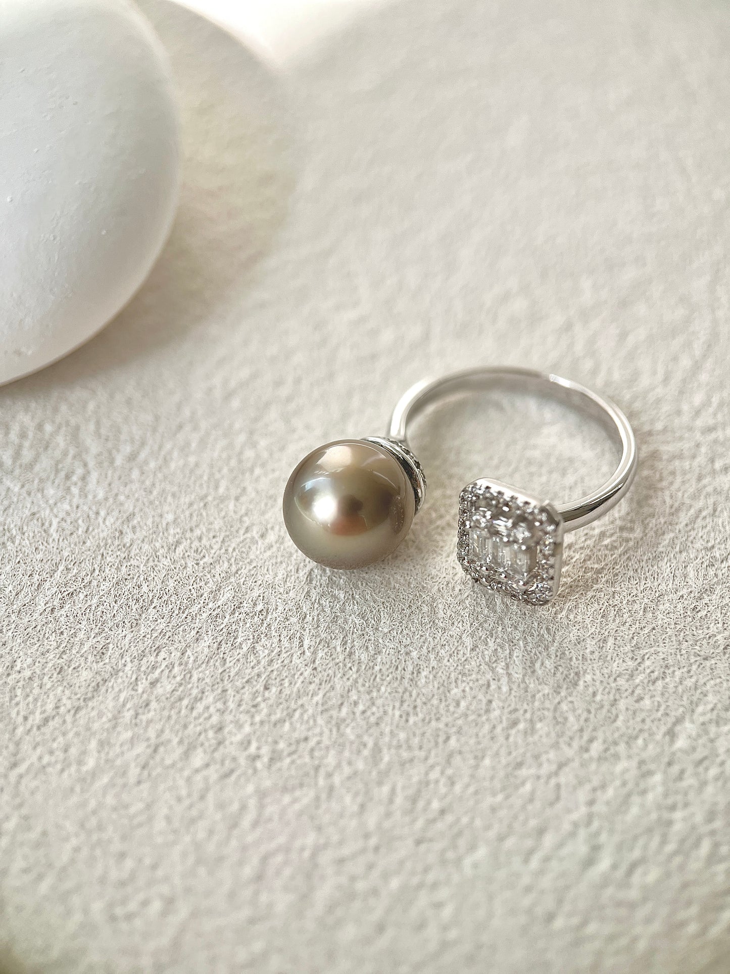 Silver ring with a tahitian black pearl and another ring with a diamond on a light gray surface