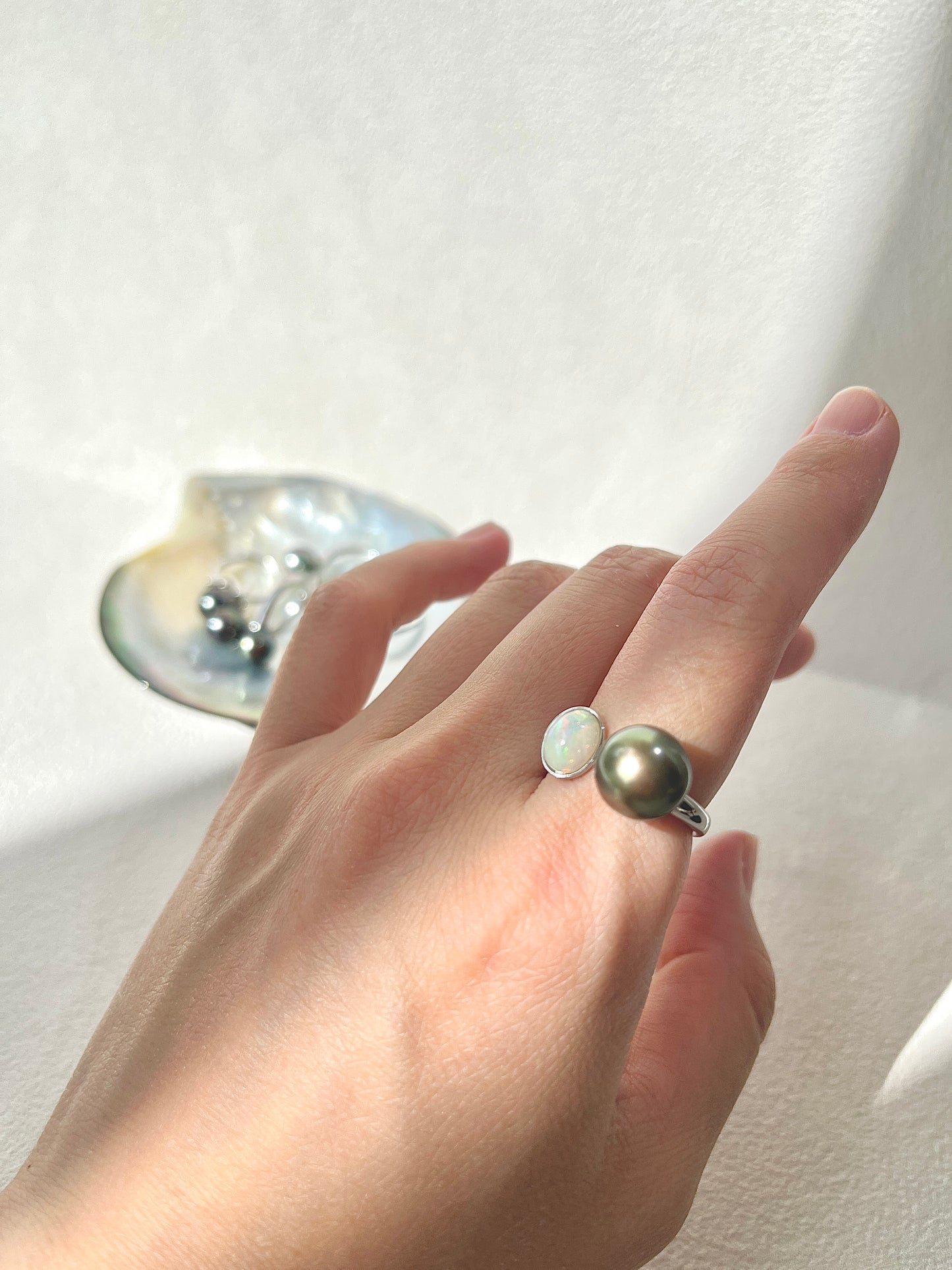 Tahitian Black pearl ring with Opal on a hand with a neutral background