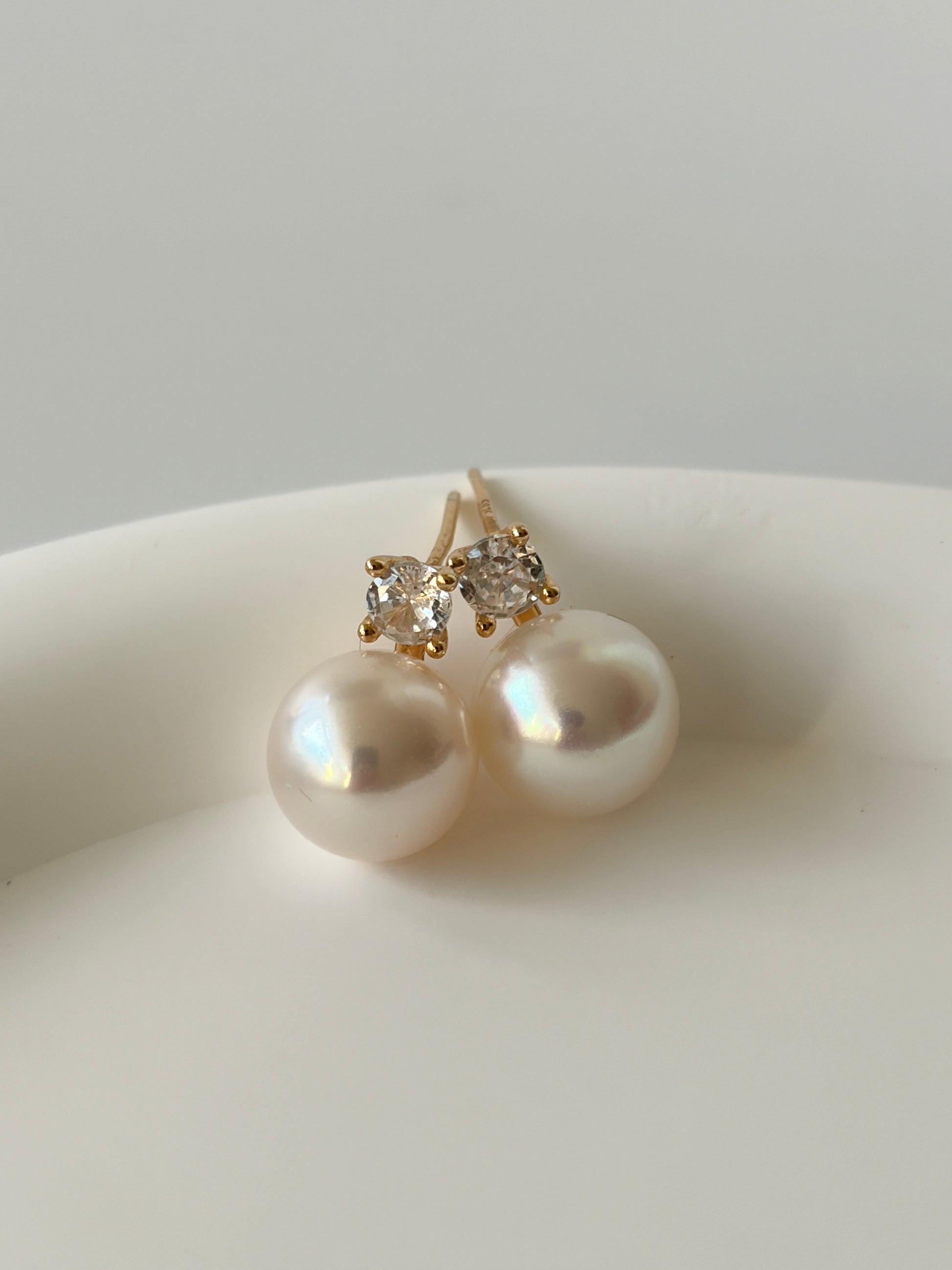 Pearl earrings with gold and diamond accents on a white surface