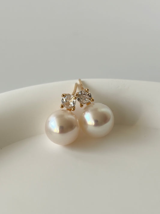 Pearl earrings with gold and diamond accents on a white surface
