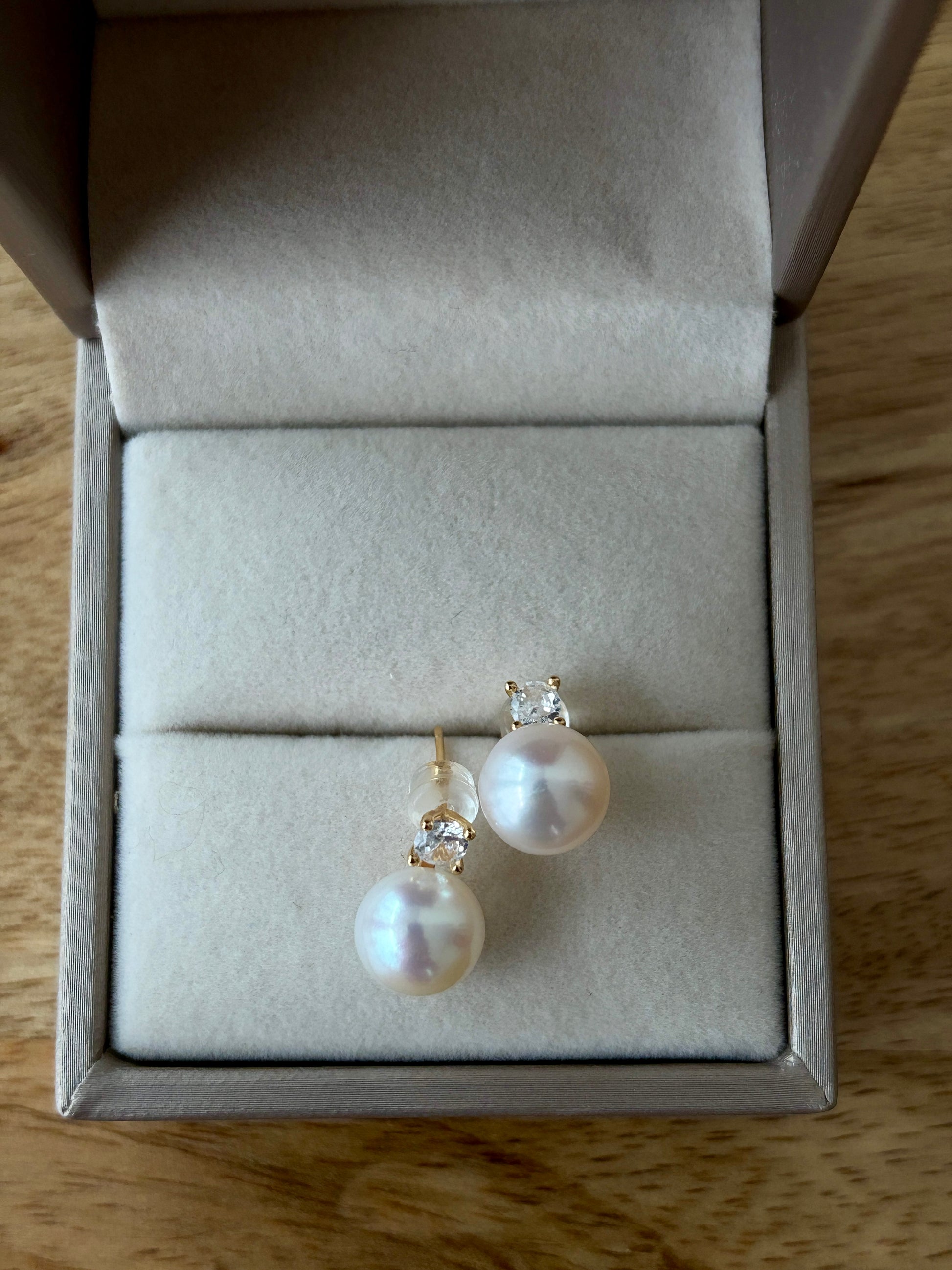 Peach Pearl stud earrings in a jewelry box on a wooden surface
