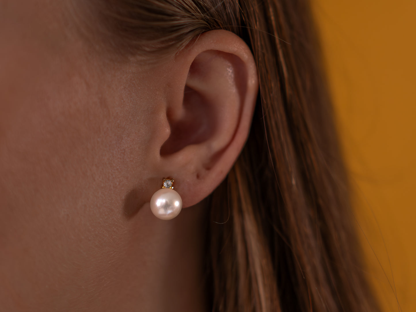 Close-up of an ear wearing a pearl earrings with a blurred background