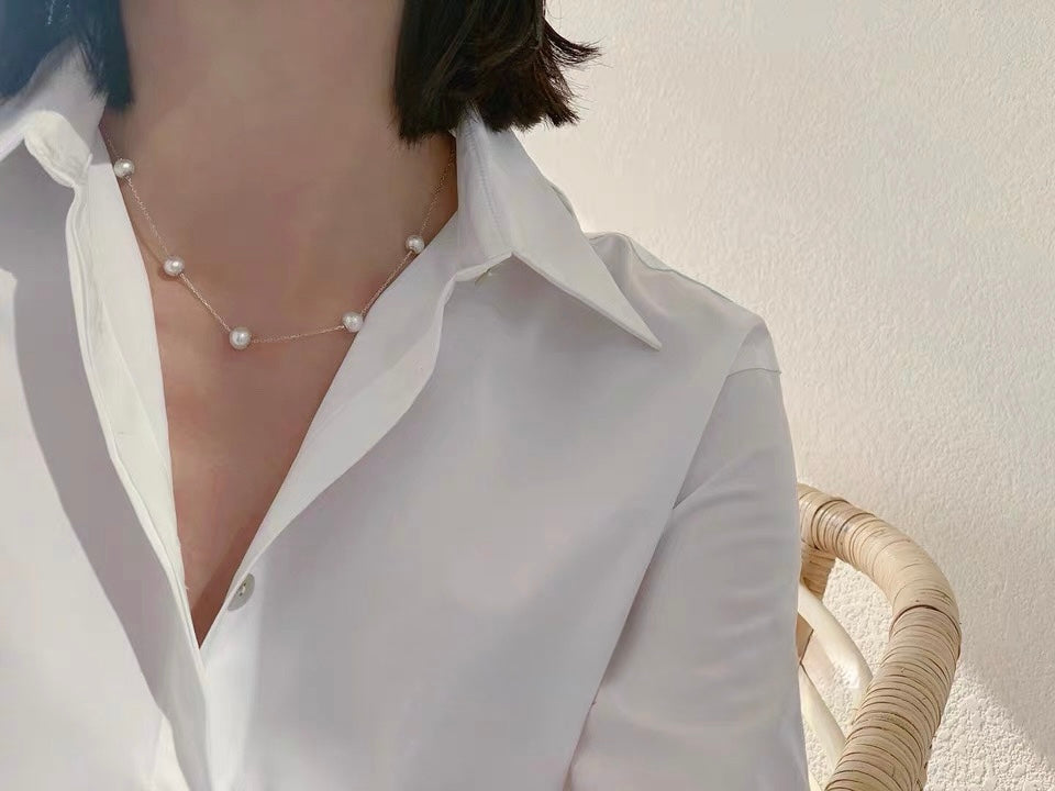 Woman wearing an adjustable freshwater pearl necklace with 18K solid gold chain and round pearls.