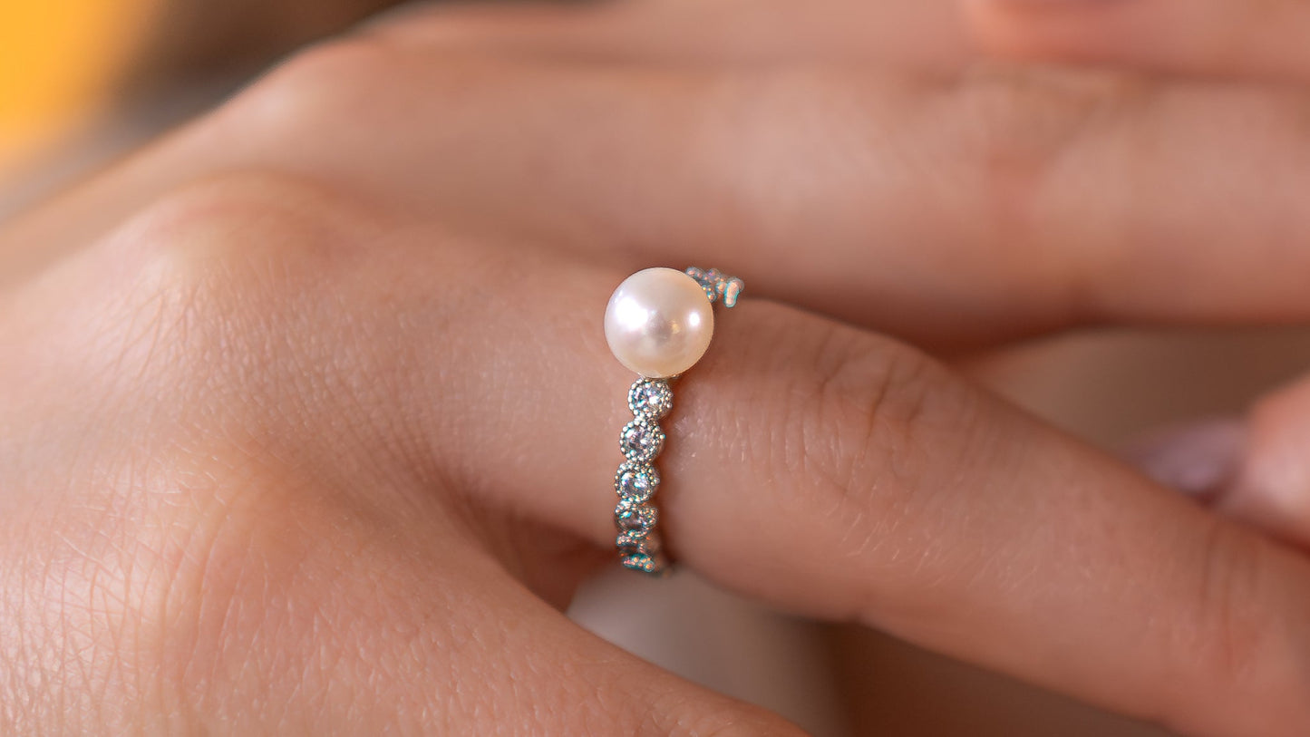 Close-up of hands wearing pearl rings with a blurred background