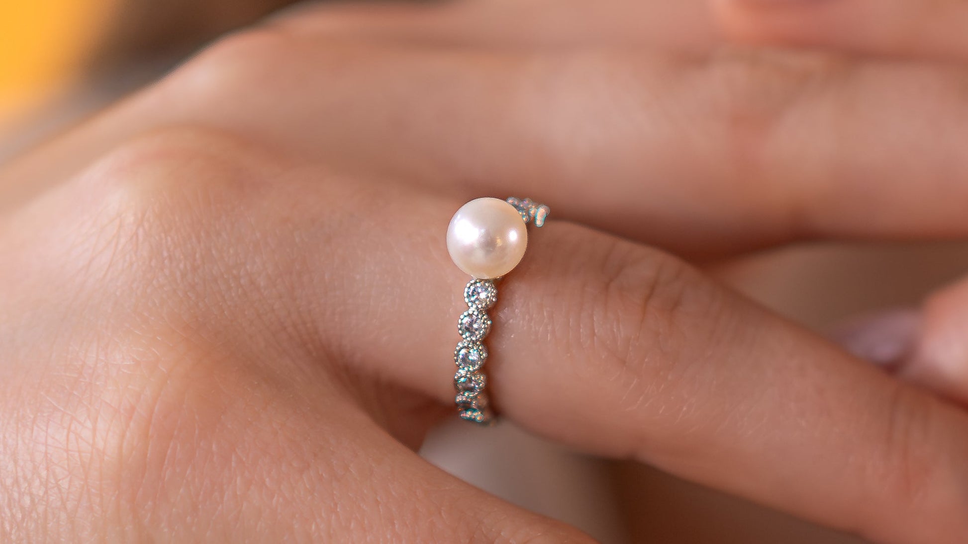 Close-up of hands wearing pearl rings with a blurred background