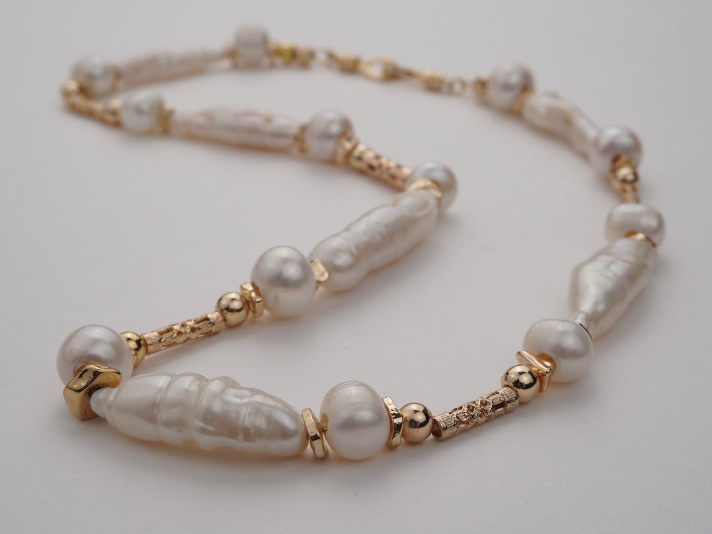 Pearl necklace with gold accents on a light gray background