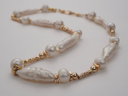 Pearl necklace with gold accents on a light gray background