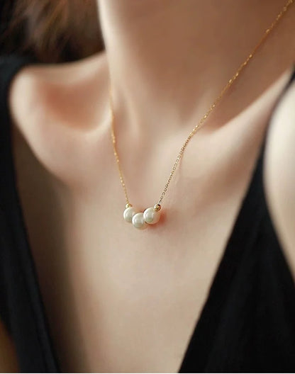 Gold necklace with three pearls worn by a person