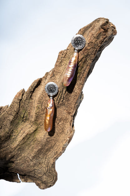 Pair of earrings with baroque pearls on a wooden surfaces