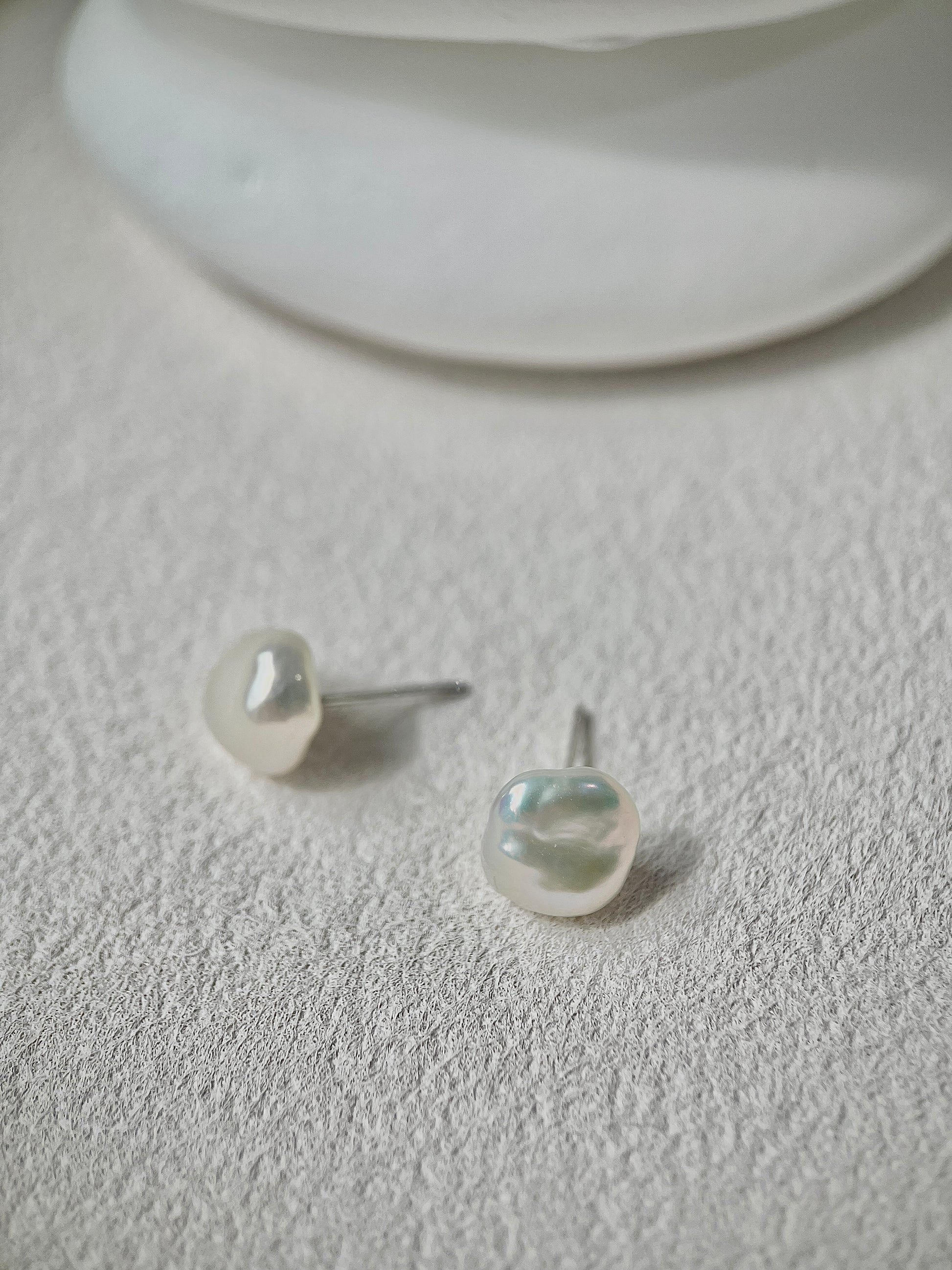 Pearl earrings on a textured white surface