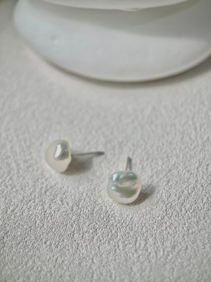 Pearl earrings on a textured white surface