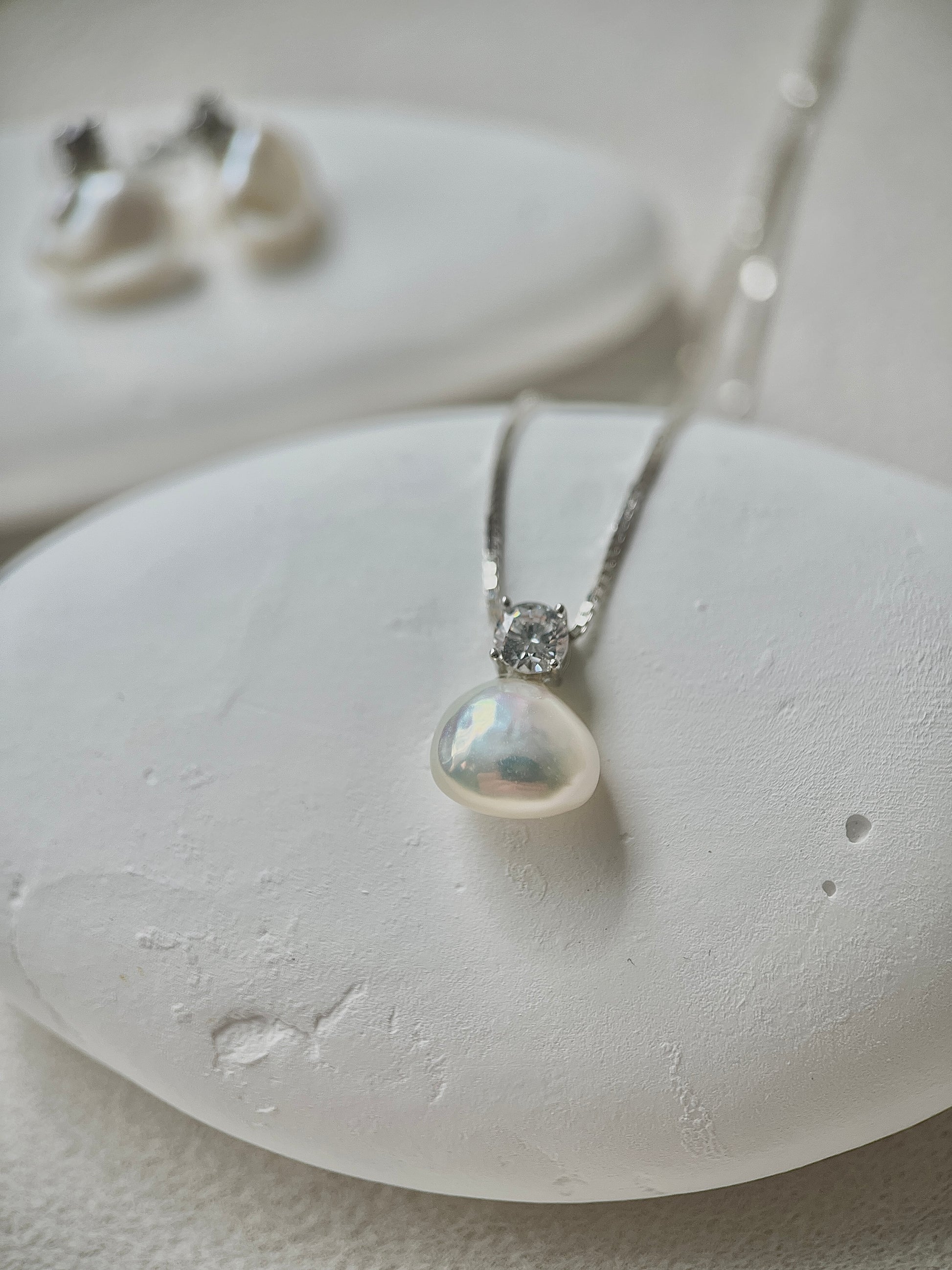 Pearl necklace with silver chain on a white stone surface