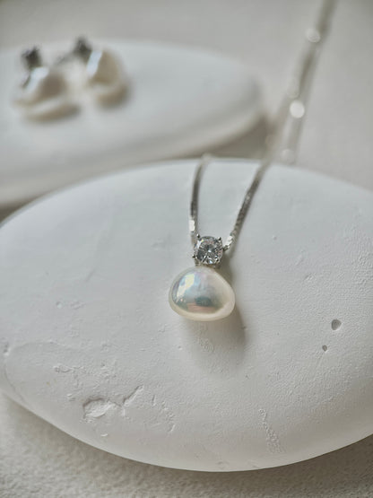 Pearl necklace with silver chain on a white stone surface