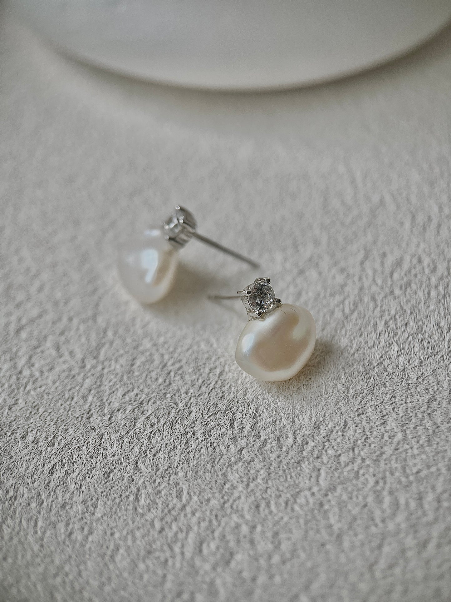 Pearl earrings on a textured white surface