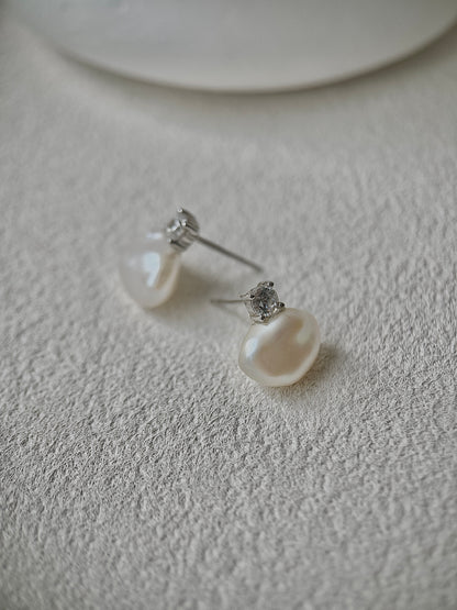 Pearl earrings on a textured white surface