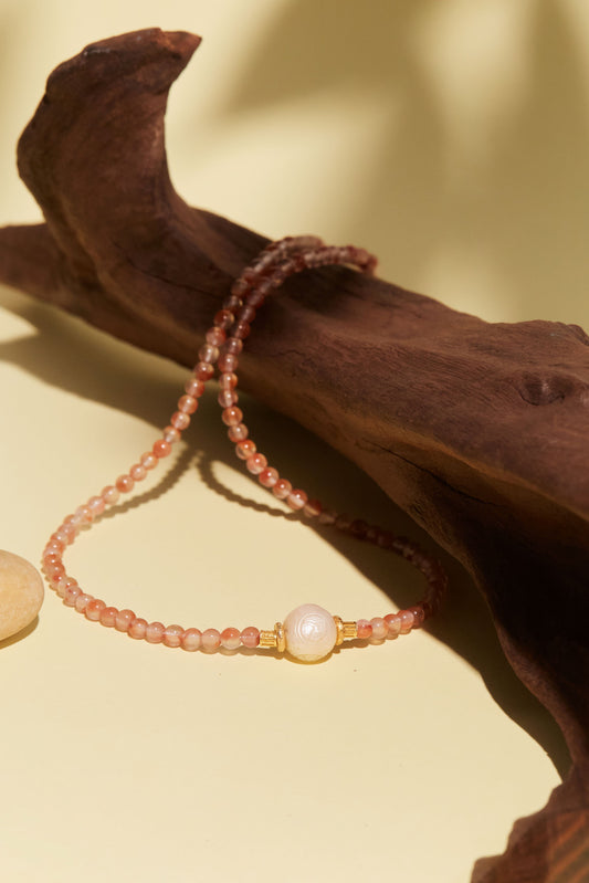 Beaded bracelet with a white freshwater pearl on a wooden surface