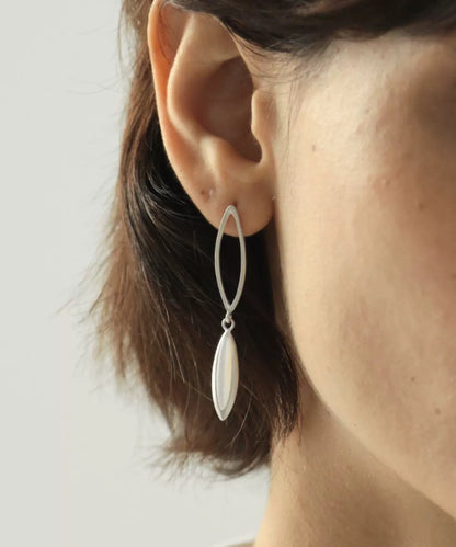 Close-up of a person wearing a silver earring with a plain background