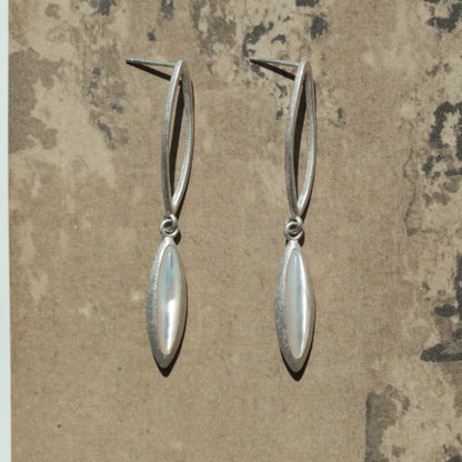 Pair of silver earrings on a textured beige background