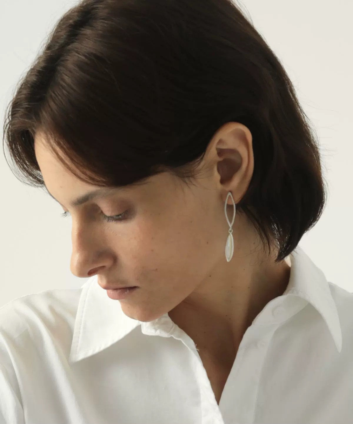 Close-up of a person wearing a silver earring with a white background