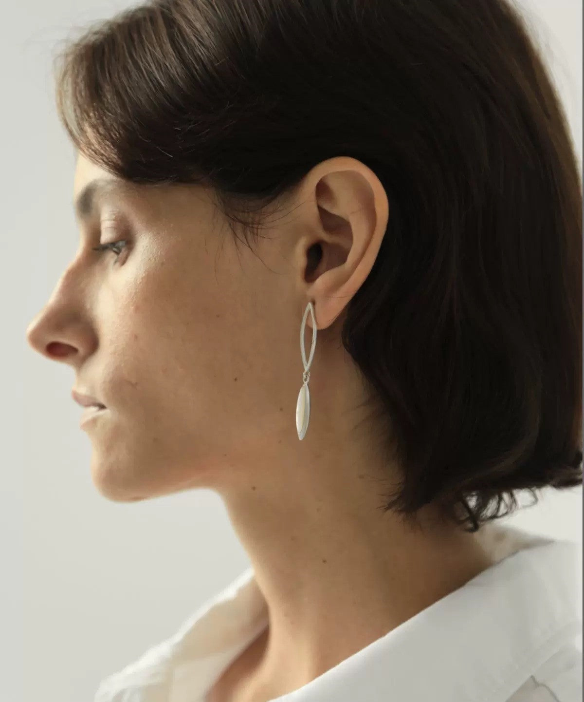 Close-up of a person wearing a silver earring with a white background