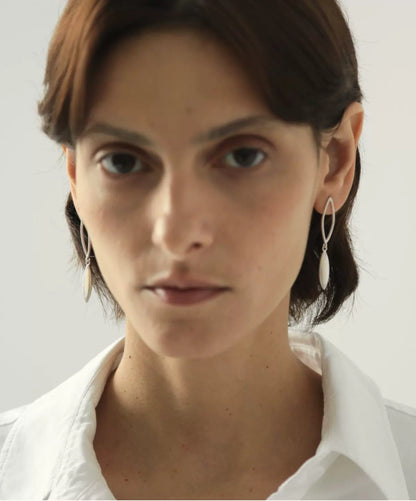 Close-up of a person wearing earrings with a plain background