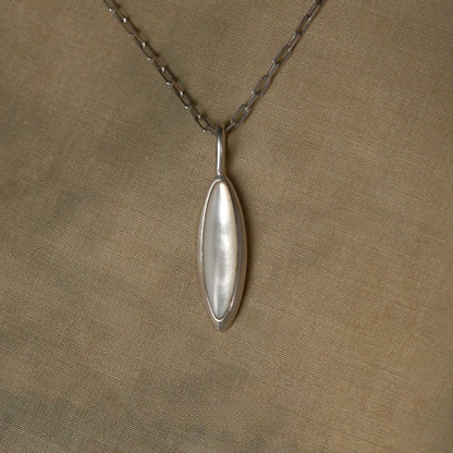 Silver nacre pendant necklace on a beige fabric background