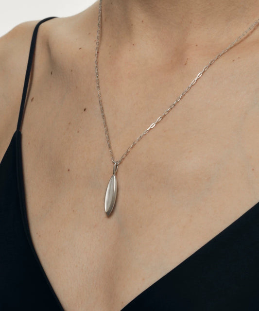 Silver necklace with a nacre pendant on a person wearing a black top.