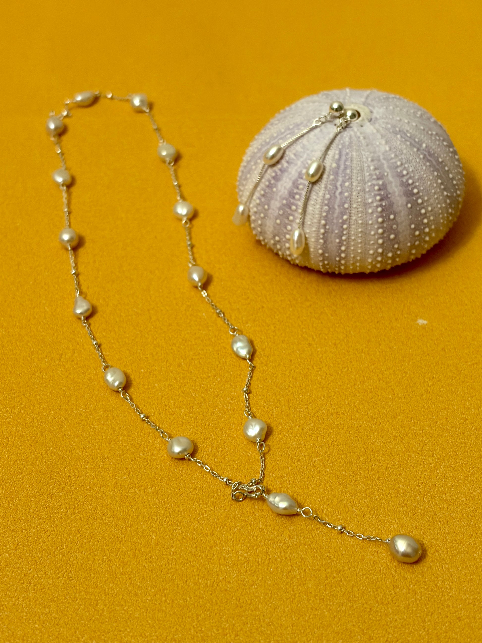 Pearl necklace with a shell on a mustard yellow background