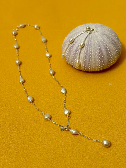Pearl necklace with a shell on a mustard yellow background