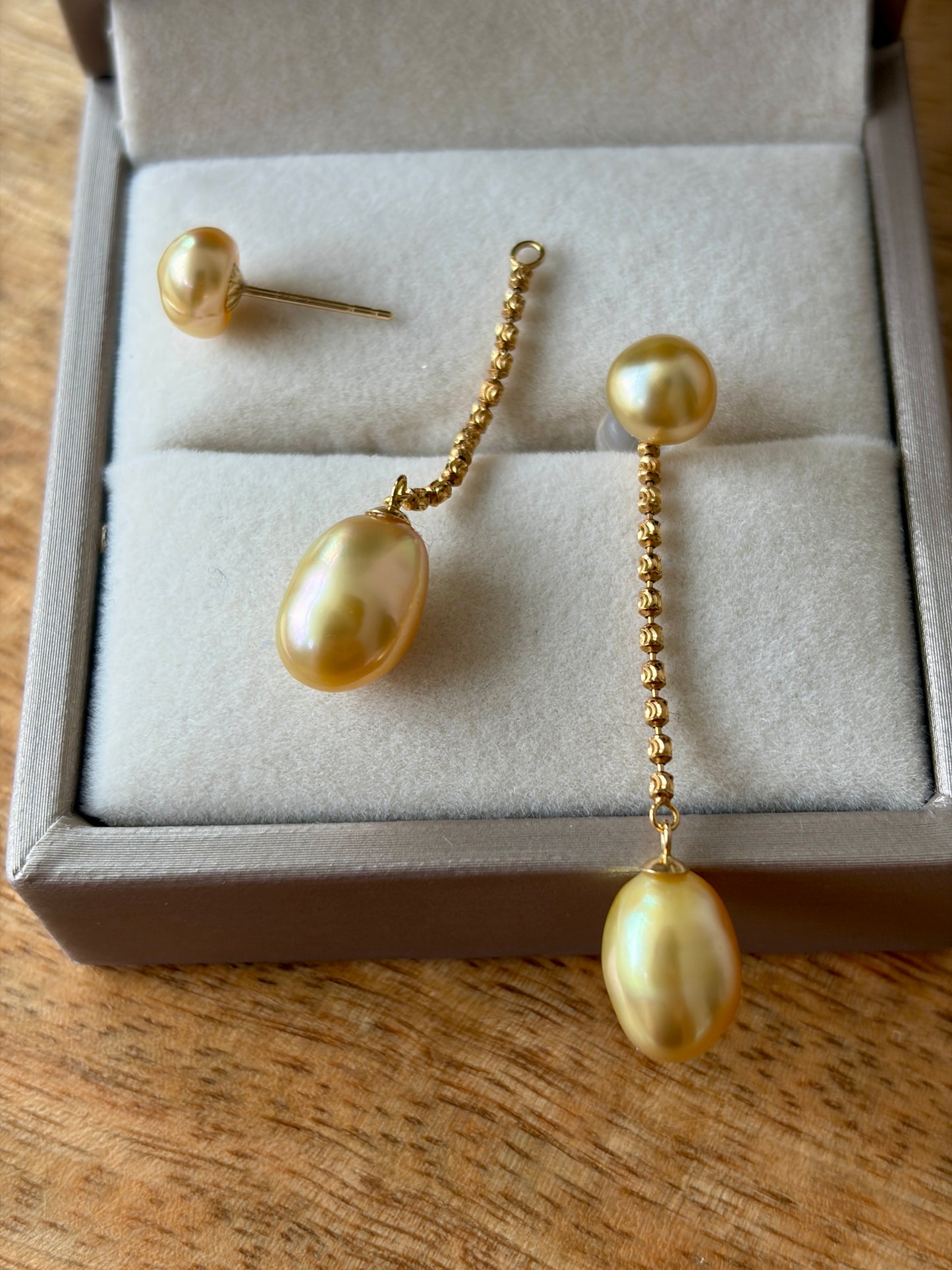South sea golden pearl earrings, featuring Keshi pearls and 18K solid gold in a jewelry box on a wooden surface