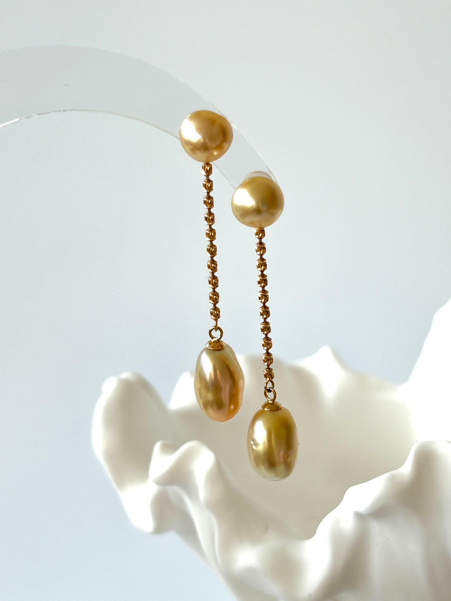 South Sea Golden pearl earrings in 18K solid gold setting on a white shell against a light gray background