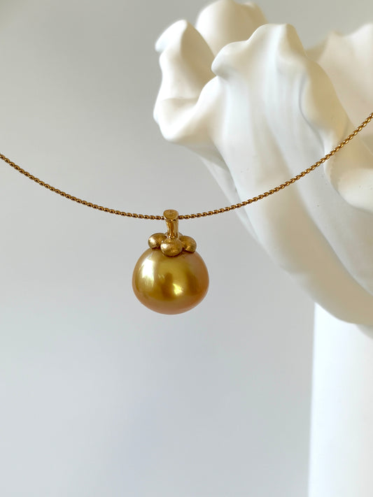 Gold necklace with a south sea golden pearl pendant on a white background