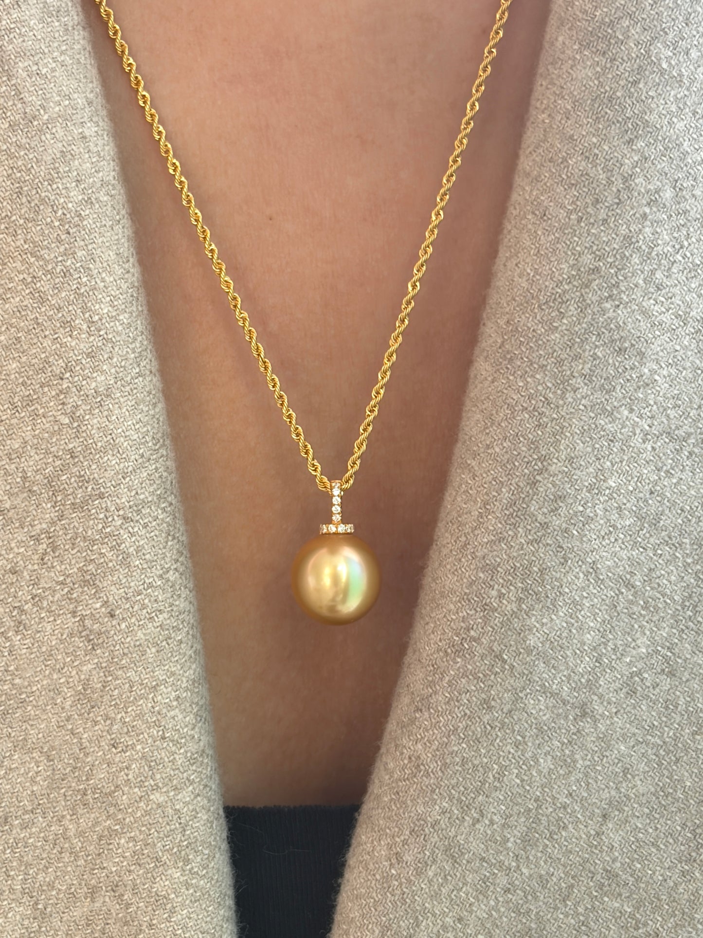 Gold necklace with a south sea golden pearl pendant worn by a person against a neutral background