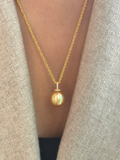 Gold necklace with a south sea golden pearl pendant worn by a person against a neutral background