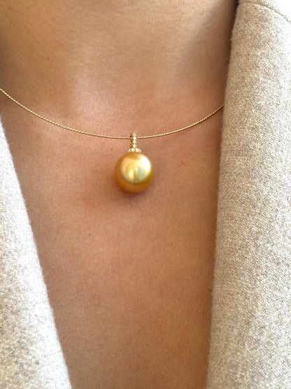 Gold necklace with a large south sea golden pearl pendant on a person's neck.