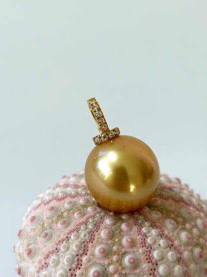 Golden pearl pendant on a textured white surface
