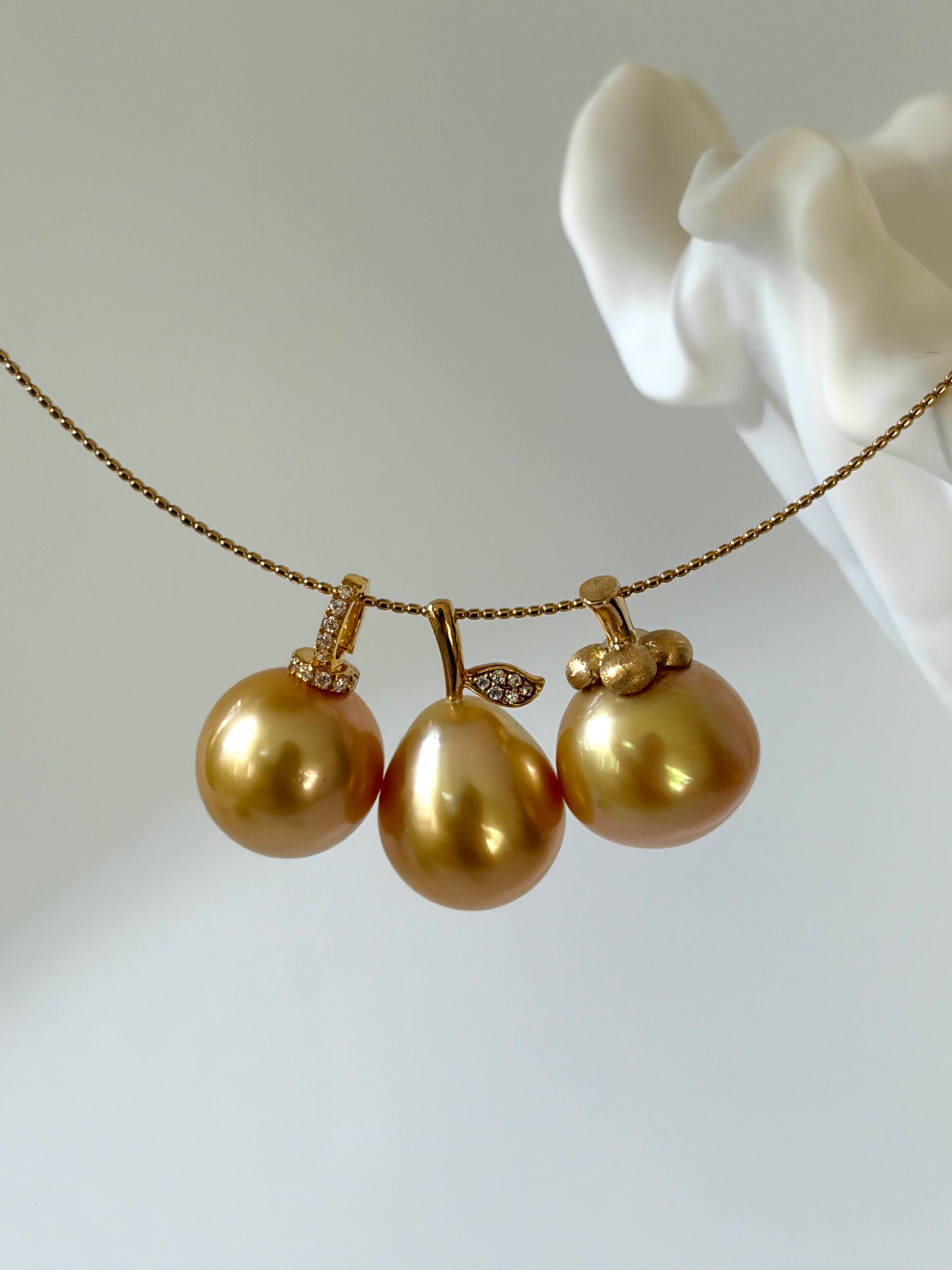 three south sea golden pearl pendants on a white background