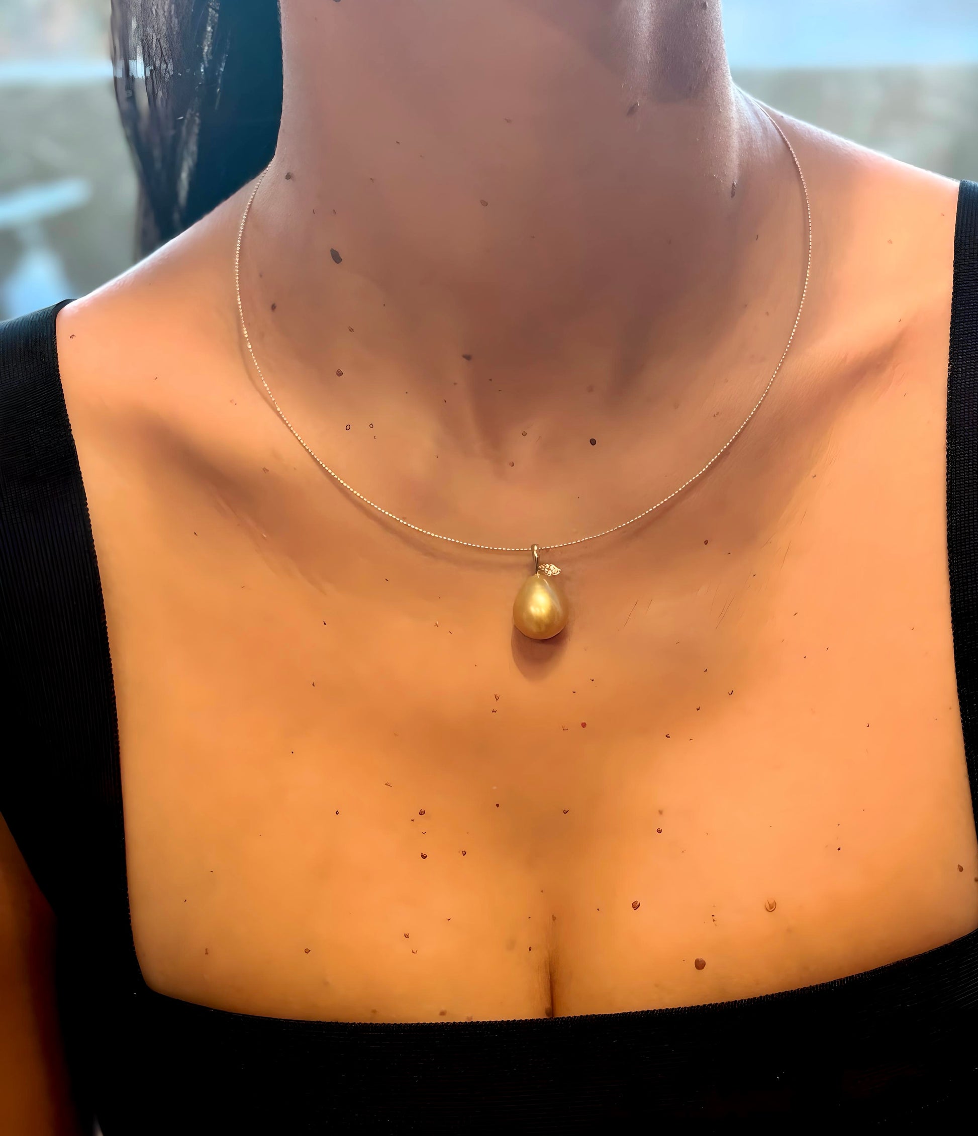Women wearing south sea golden pearl pendant with shimmering accent in 18K gold