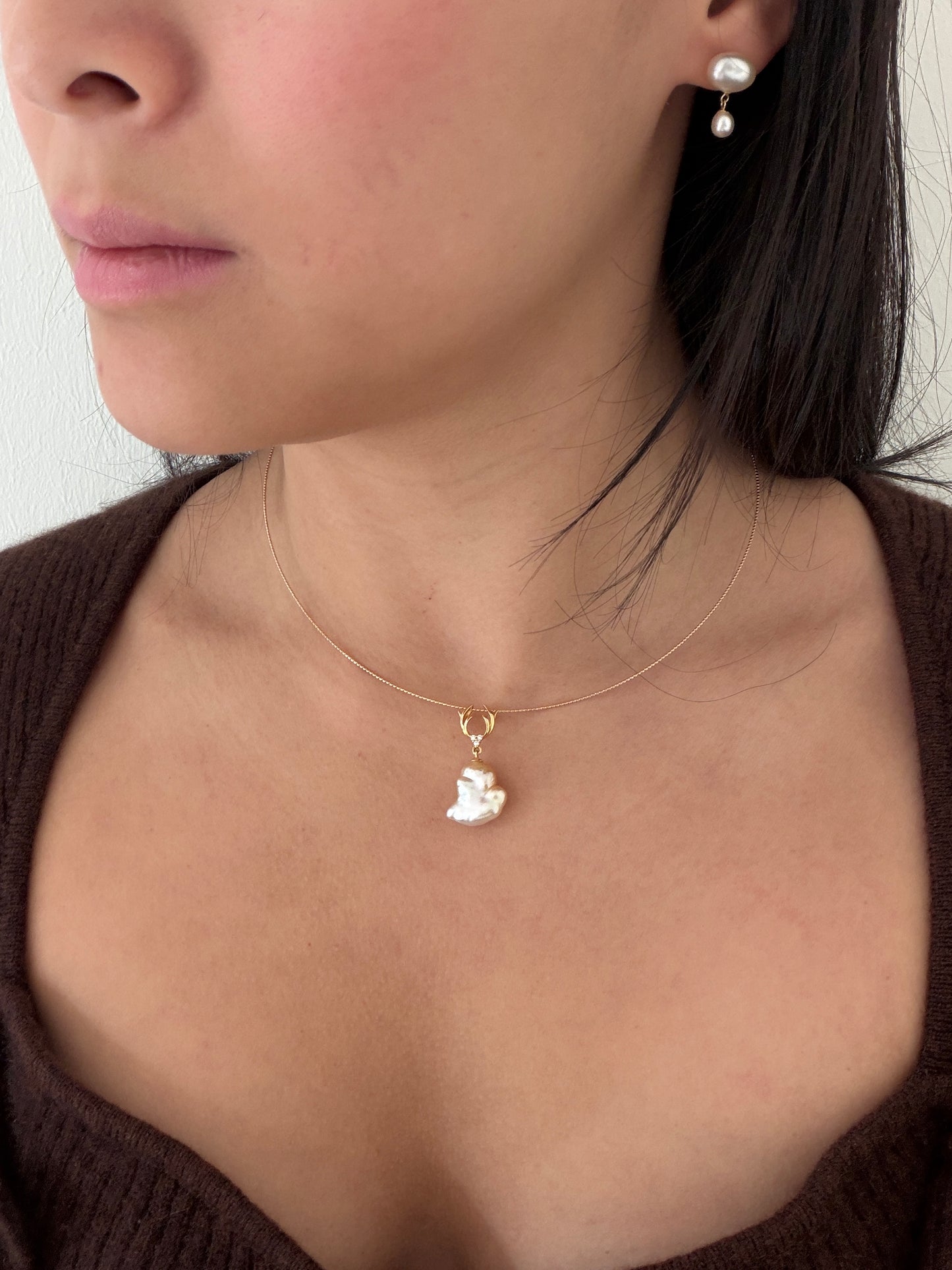 Close-up of a person wearing a South Sea golden pearl pendant on a gold necklace