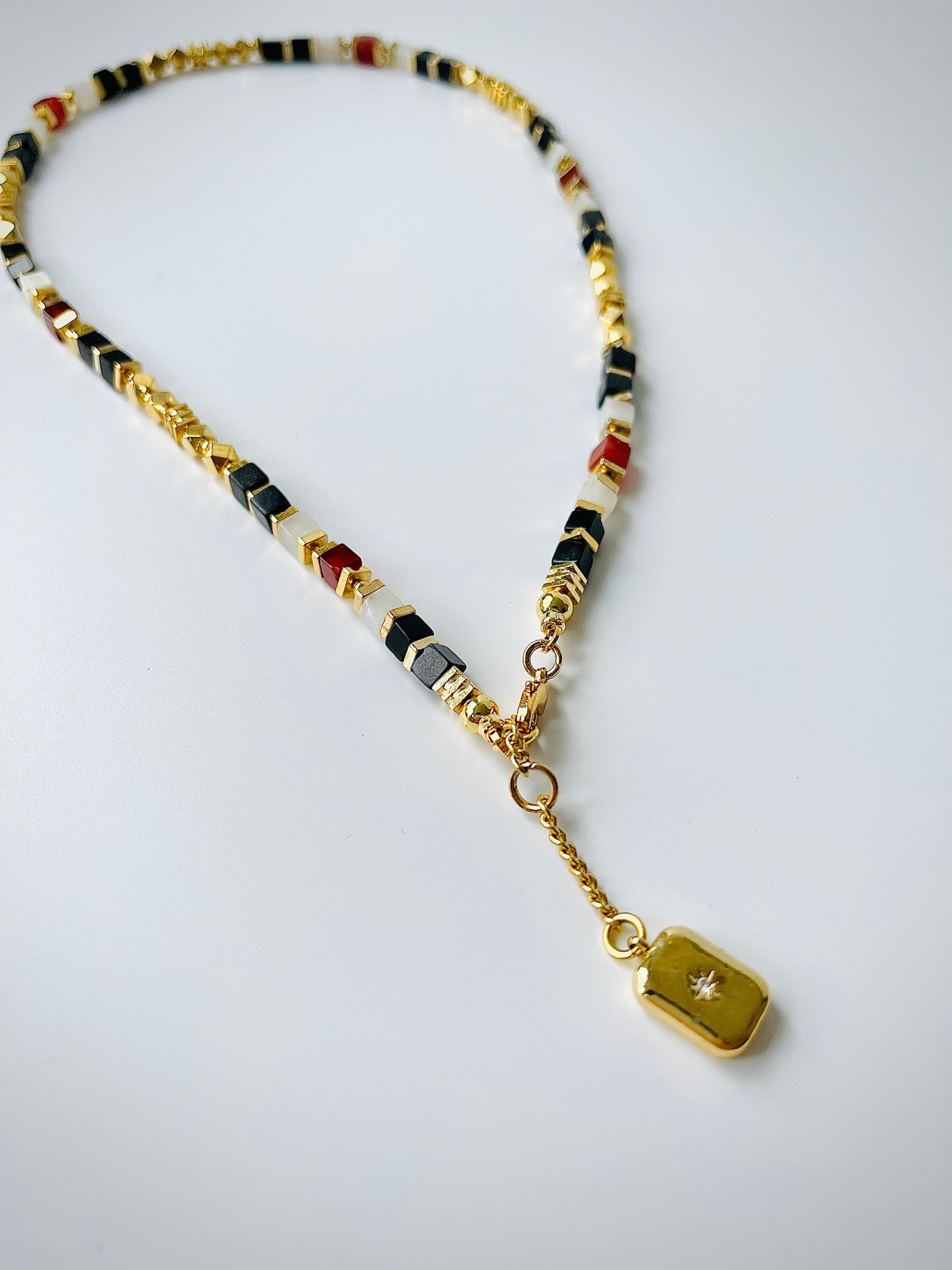 Necklace with agate beads and a gold tag on a white background
