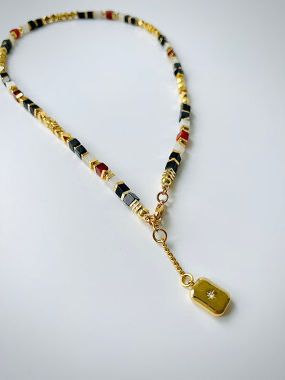 Necklace with agate beads and a gold tag on a white background
