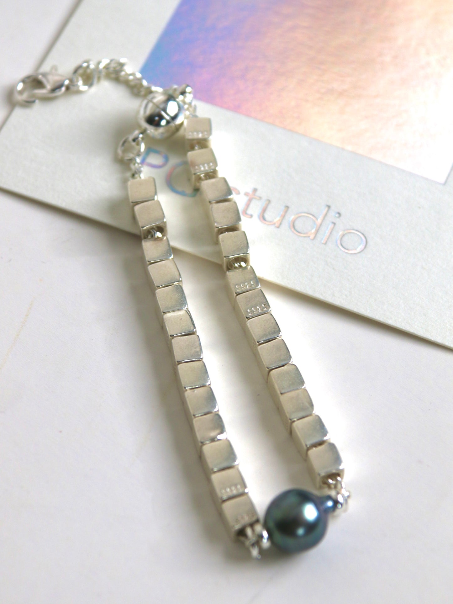 Silver bracelet for men with black Tahitian pearl on a white surface