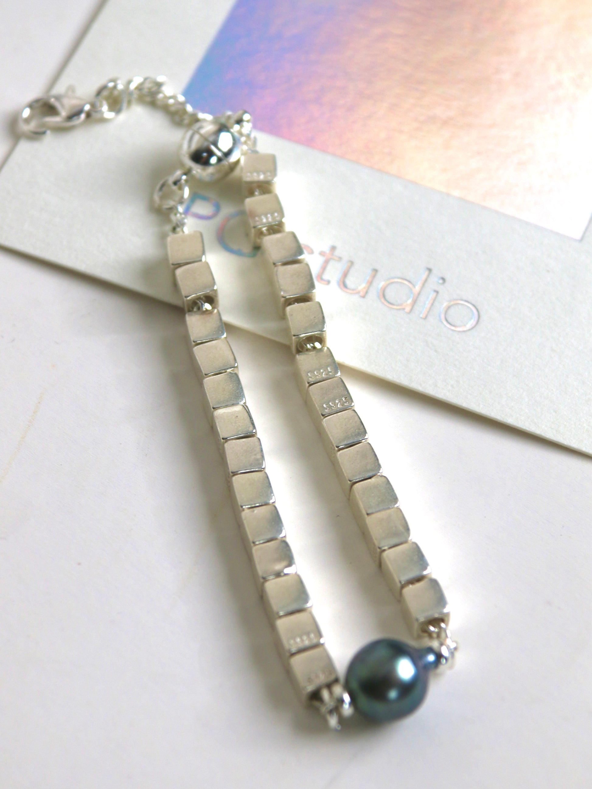 Silver bracelet for men with black Tahitian pearl on a white surface